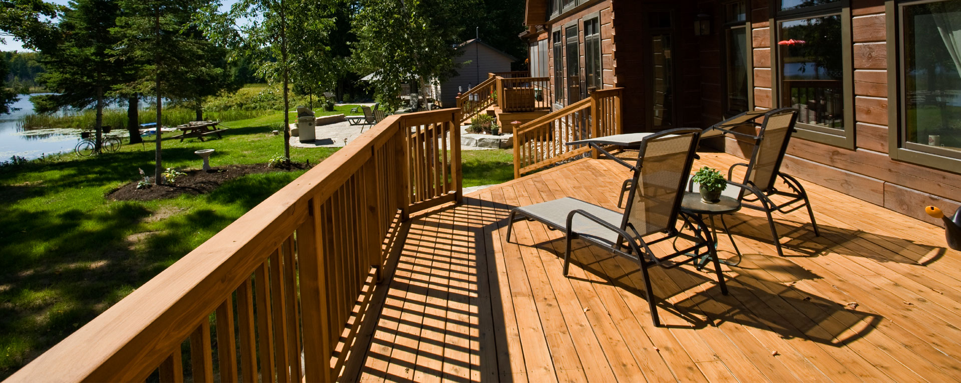 Cedar lakefront cottage deck with railings and lounge chairs