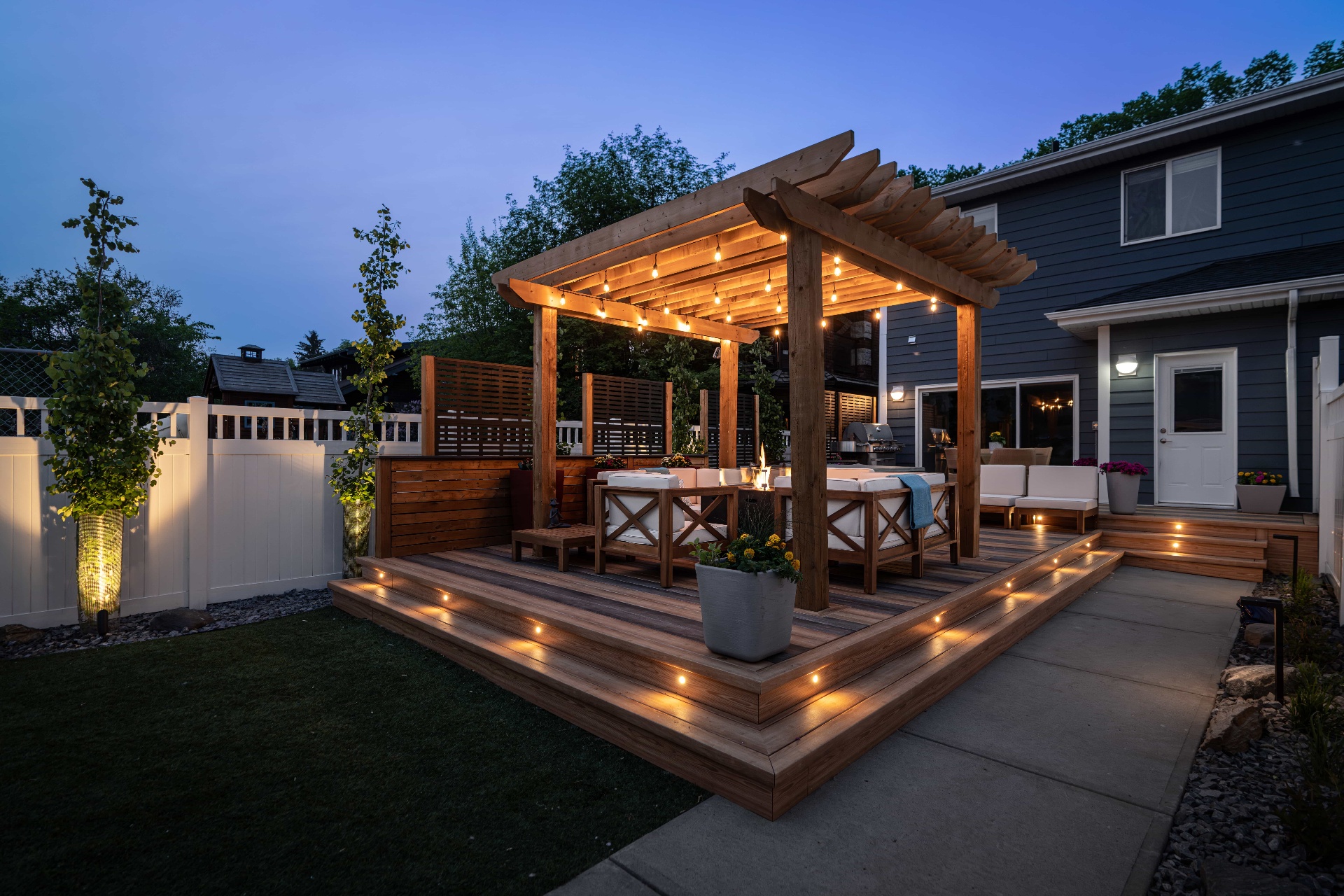 Backyard deck with cedar pergola and string lights at twilight